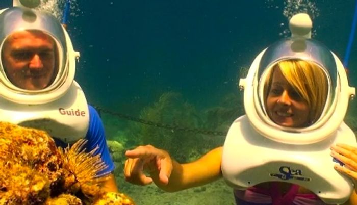 a couple observing a coral reef while helmet diving in the Caribbean