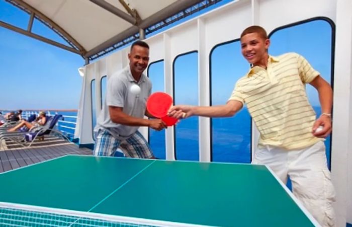 A father and son enjoying a game of ping pong on a Dinogo cruise ship.