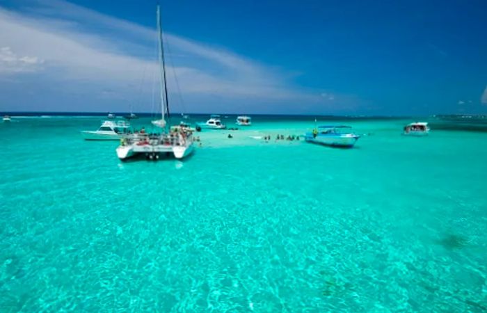 tourists swimming around boats and playing with stingrays in Stingray City, Grand Cayman