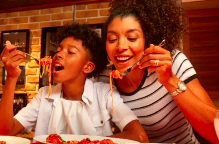 A mother and son enjoying spaghetti and meatballs on a Dinogo cruise.