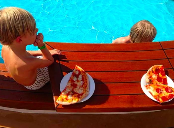 kids swimming and enjoying pizza by the pool