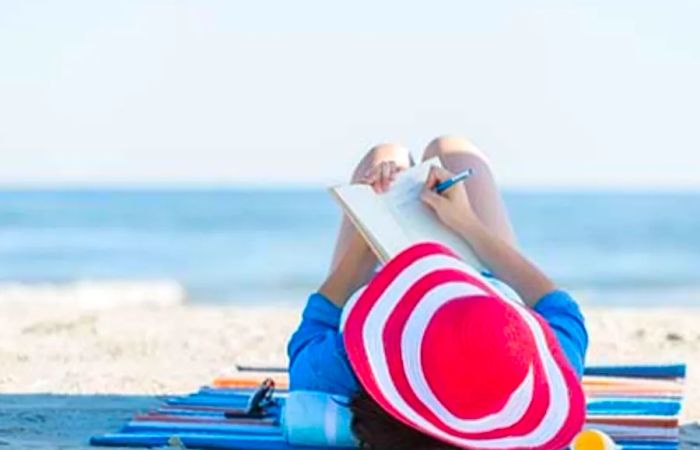 woman journaling while relaxing on the beach