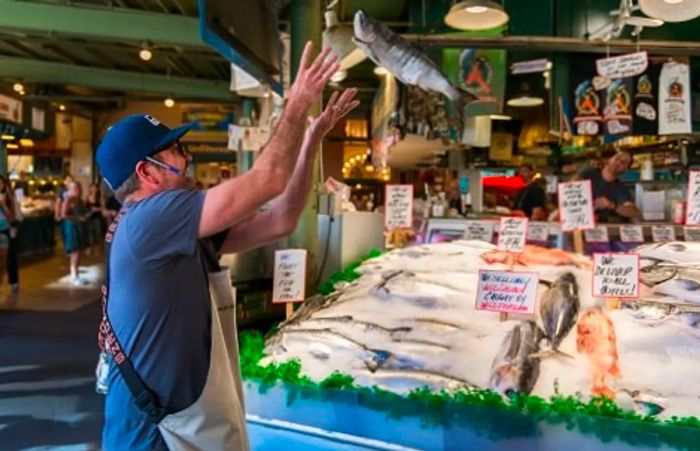 a man throwing fresh fish at the local farmers market in the Pike Market area