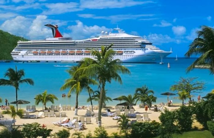 a view of a Caribbean beach with Dinogo Triumph anchored in the background