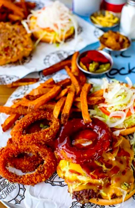 Burger topped with onion rings and served with fries