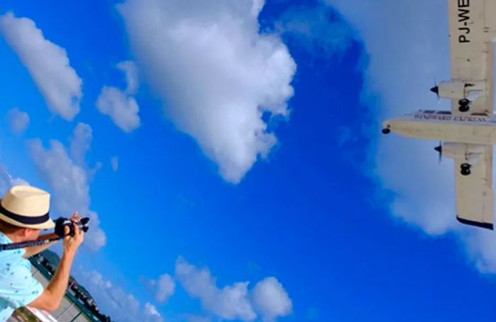 Jeremy snapping a picture of a plane soaring overhead at Maho Beach.