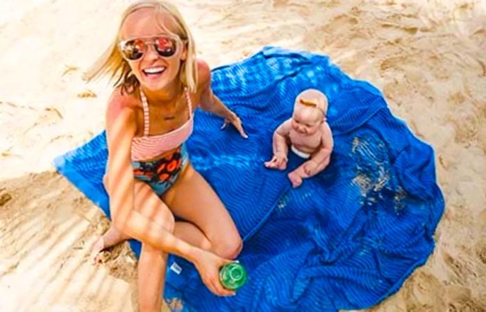 Hailey and her daughter relaxing on a blue blanket by the beach