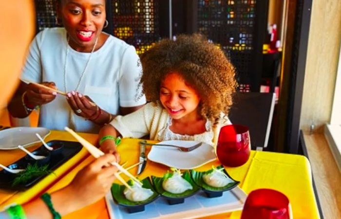 a young girl using chopsticks to pick up a dumpling at Ji Ji Asian Kitchen