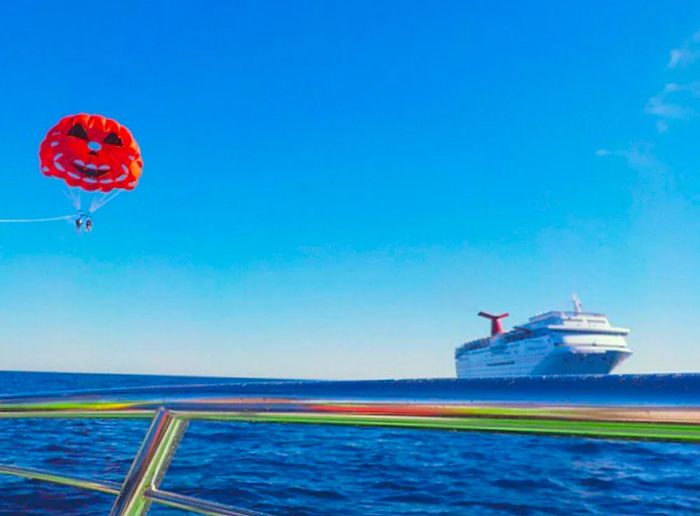 two individuals parasailing over Catalina Island with a Dinogo cruise ship visible in the background