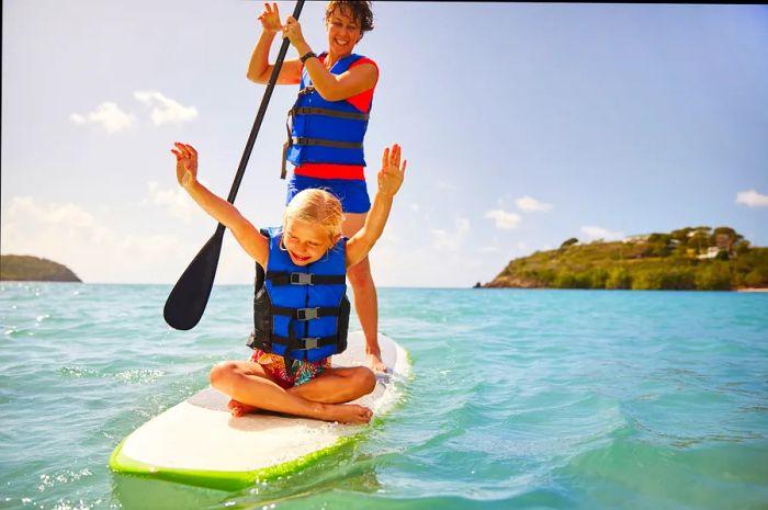 a woman and a young girl raising their arms on a paddleboard