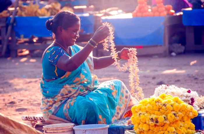 A flower vendor, unidentified, sells flowers in the bustling flower market, known as the largest flower market in Chennai.