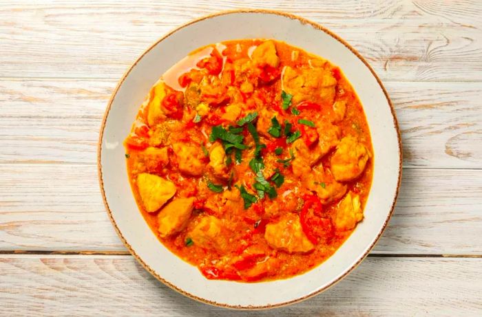 A delectable chicken curry served on a wooden table, top view