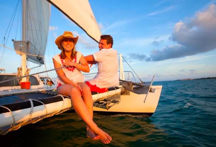 A couple laughing together at the edge of a catamaran off Antigua’s coast.