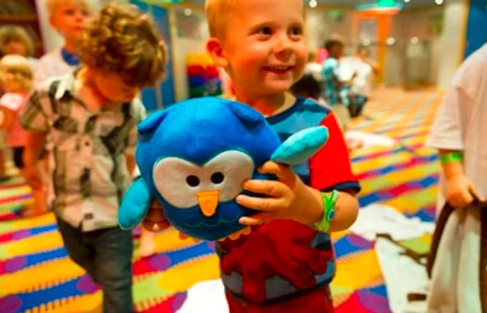 a little boy joyfully holding a plush blue owl