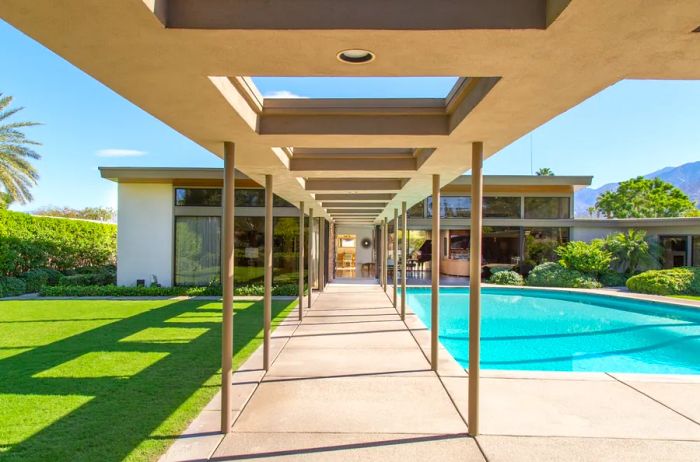 A contemporary home featuring a lush green lawn and a private in-ground pool