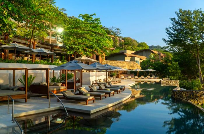 The adults-only pool at Andaz Costa Rica at Peninsula Papagayo, featuring vacant beige lounge chairs and sunshades