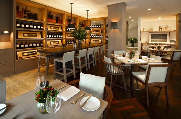 The restaurant at Las Alcobas, a Luxury Collection Hotel, offers a refined space with wood floors and white chairs surrounding sleek square tables.