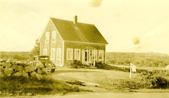 A vintage black-and-white photo of a gray shingled house from the 1950s with an old car parked outside. This was the home of Katie West, the last fluent speaker of Martha’s Vineyard Sign Language.