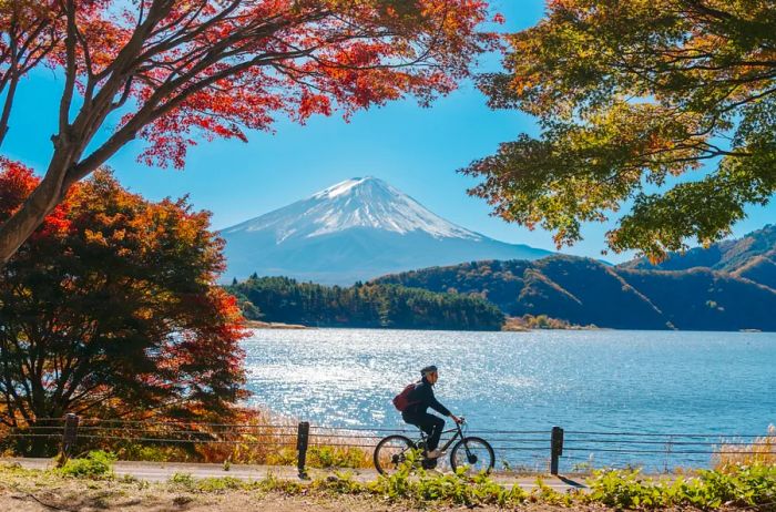 A cyclist rides near a lake with the majestic Mount Fuji in the background