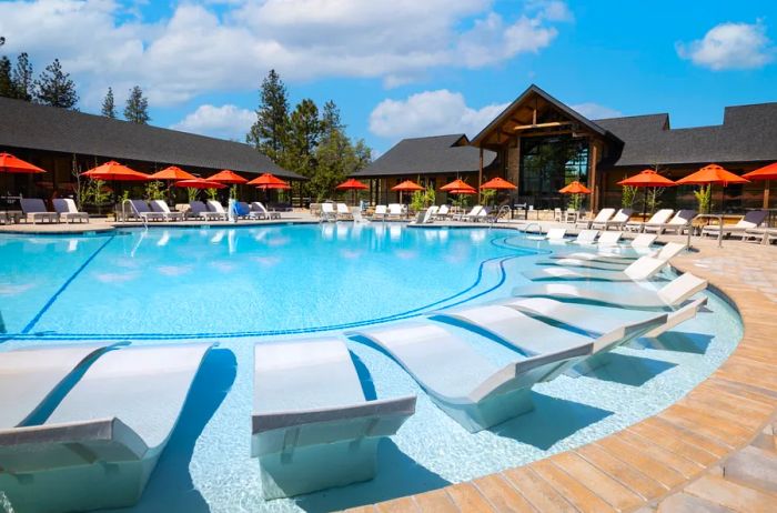 The outdoor pool at Firefall Ranch, surrounded by lounge chairs and shaded by bright orange umbrellas.