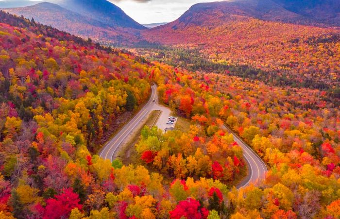 An aerial shot of the Kancamagus Highway snaking through a vibrant forest of fall colors