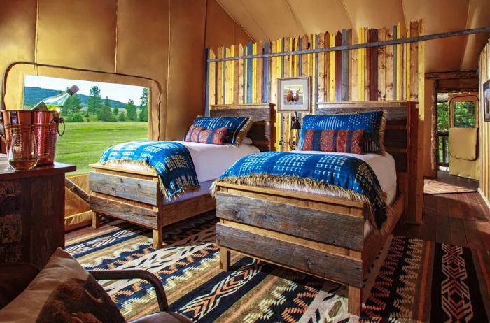 Interior view of a guest room at the Resort at Paws Up, featuring a black, tan, and white geometric patterned rug alongside two wood-trimmed beds.