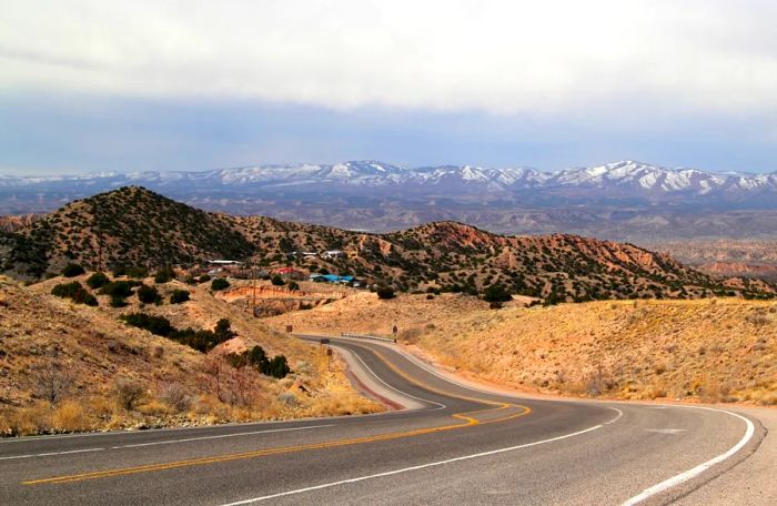 A desert-brown landscape along the High Road to Taos, Northern New Mexico, with snow-capped mountains in the distance