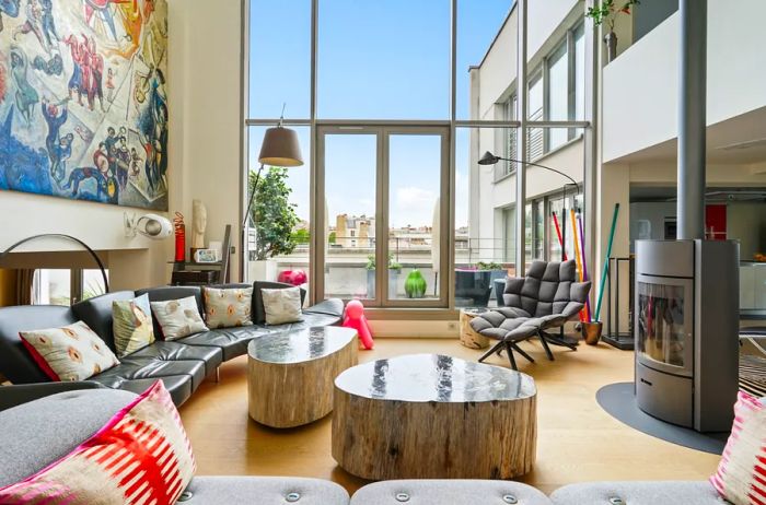 Modern living room in Paris featuring high ceilings, a fireplace, and glass doors leading to a deck.