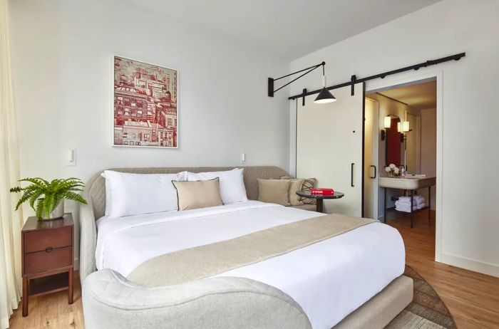 A Chamber King room at Virgin Hotels New York, featuring a large bed, minimalist design, and light wood flooring.