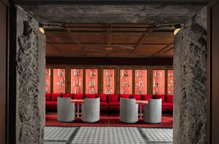 A bar adorned with red cushions, round seating, a checkerboard floor, and a showcase of trophies