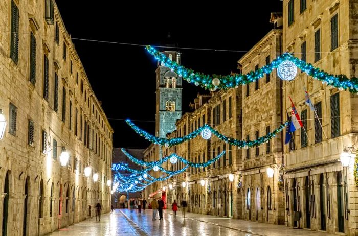 A picturesque street in Dubrovnik's ancient city center during December, adorned with blue garlands and lights.