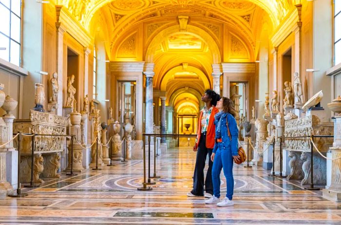 A black woman and a white woman enjoying their time in the Vatican Museum without any other visitors around.