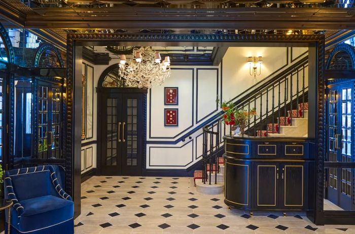 The lobby and reception area showcase a palette of white and navy blue, accented with gold details, featuring a chandelier and a staircase.