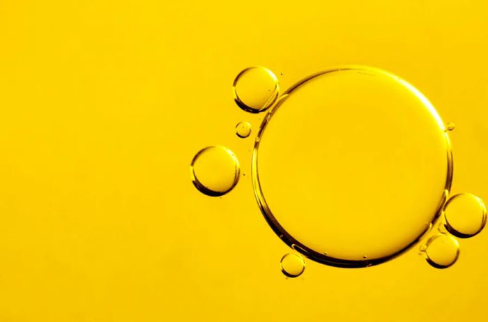 A close-up view of warm yellow biofuel featuring magnified, round droplets suspended on the surface.