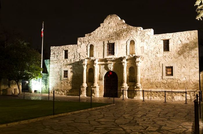 The Alamo in San Antonio, Texas, a historic Spanish mission and fortress constructed of stone, as seen illuminated at night.