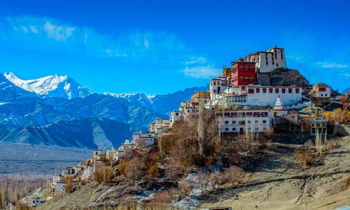 A cluster of buildings set on a hill with mountains in the background