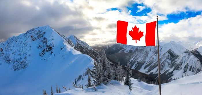 A Canadian flag waves over snow-laden peaks