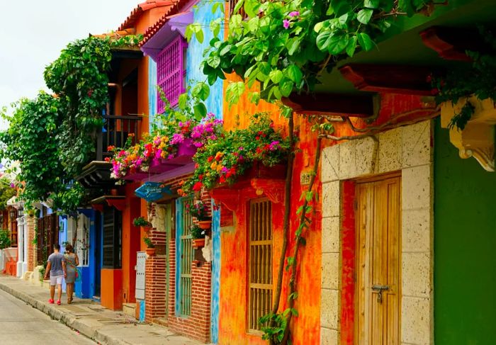 A street in Cartagena, Colombia, is adorned with colorful houses and lush floral beds.