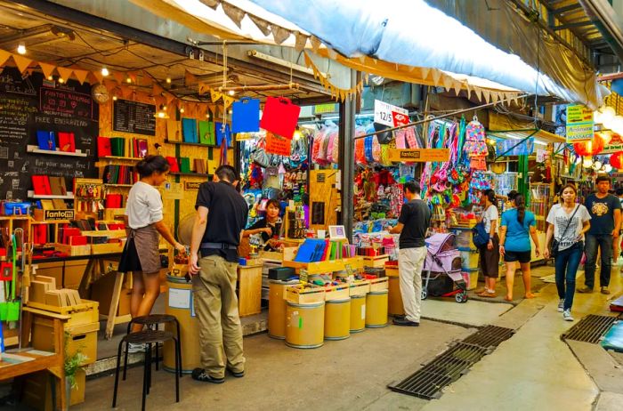 Shoppers peruse the vibrant stalls at Chatuchak Market in Bangkok, Thailand.