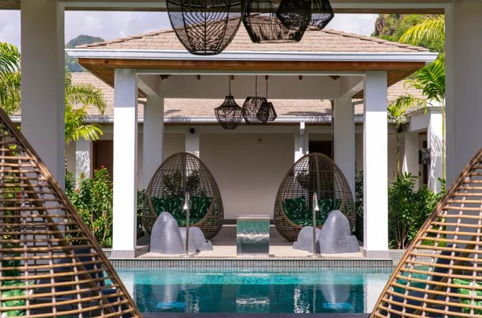 A series of dark, egg-shaped basket chairs are placed on either side of the pool at the spa.