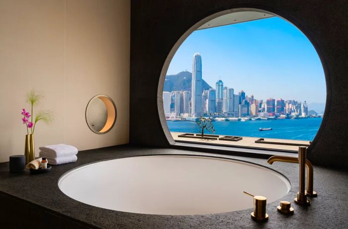 A circular bathtub in a guest room at the Regent Hong Kong, positioned by a window with views of Victoria Harbour.