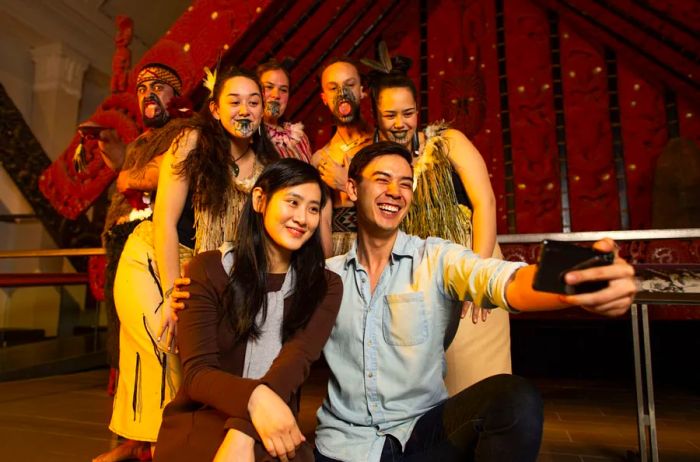 Two visitors capture a selfie with dancers at the Auckland Museum.