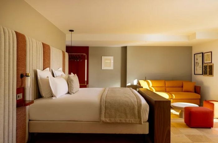 A contemporary guest room at Hotel Pilgrim in Paris, featuring a mustard-colored sofa and a large brown and white headboard that spans the entire wall.