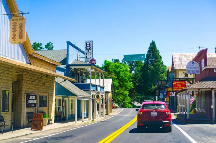 A red car heads east along Groveland's historic main street, flanked by buildings dating back to the early 20th century.