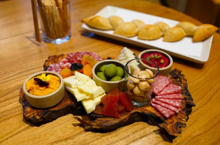 A beautifully arranged charcuterie board and artisanal baguette on a rustic wooden table