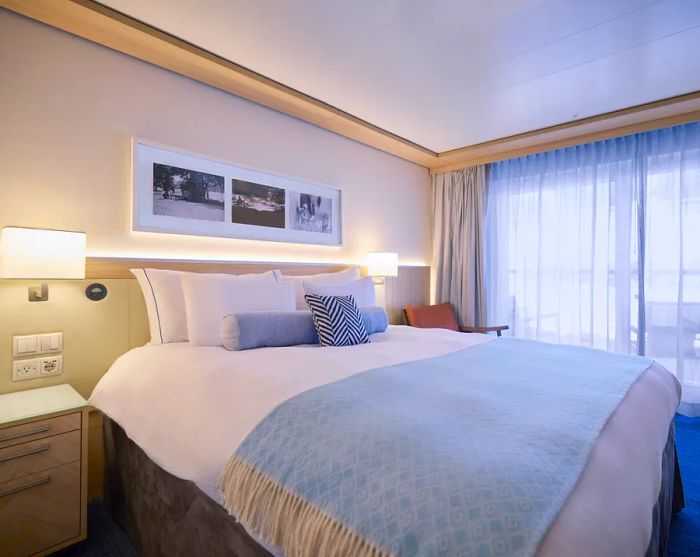 Interior view of a guest room featuring a large bed and expansive floor-to-ceiling windows.