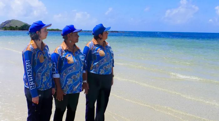 Larissa and her daughter Leilani, along with two other rangers from the Queensland Indigenous Women Rangers Network, stand on the beach gazing out at the ocean.