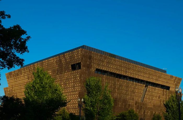 The stunning facade of the National Museum of African American History and Culture at twilight, surrounded by lush green trees.