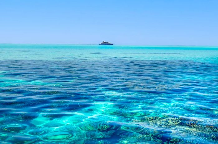 A pristine blue tropical sea with a cruise ship visible on the distant horizon.