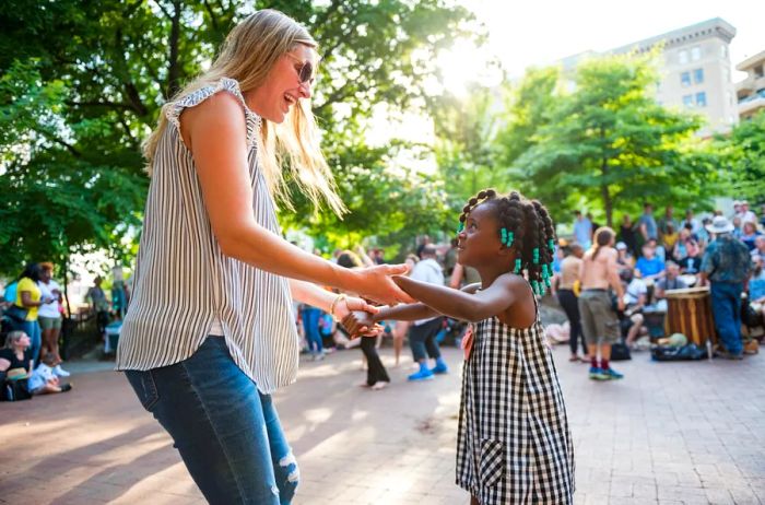 A woman and a child enjoying a dance outdoors at a drum circle in Asheville.